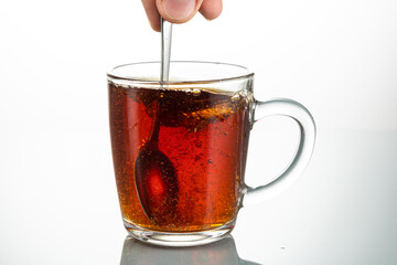 stir with a spoon a piece of sugar in a transparent mug on a white background