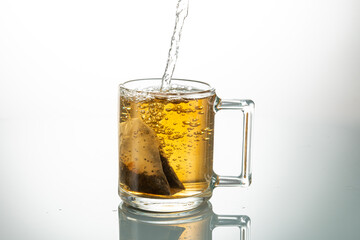 making tea from a tea bag in a transparent mug on a white background