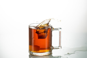 splash from falling piece of sugar in a transparent mug on a white background