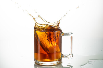 splash from falling piece of sugar in a transparent mug on a white background