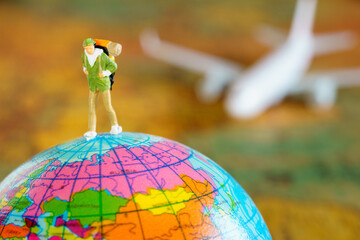 Miniature backpacker walking world toy on blur plane and map background.Traveling Concept