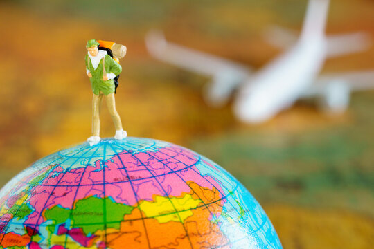 Miniature backpacker walking world toy on blur plane and map background.Traveling Concept - Powered by Adobe