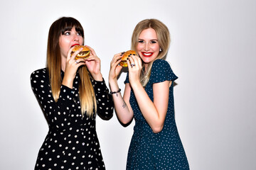 Junk food concept, two hungry woman eating huge burgers