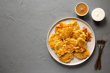 Homemade Potato Pancakes Latkes with Apple Sauce and Sour Cream on a gray background, top view. Flat lay, overhead, from above. Space for text.