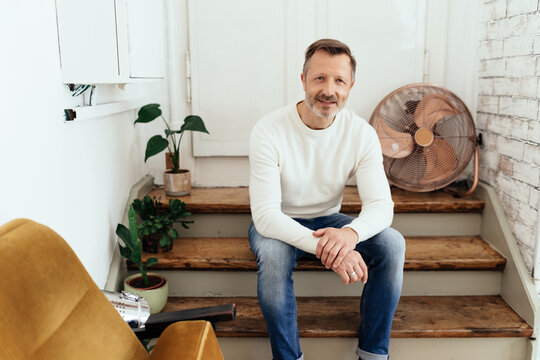 Attractive trendy middle-aged man sitting on loft steps