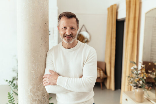Nonchalant middle-aged man standing leaning against a pillar