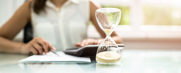 Calculating Bill Behind Sand Running Through Hourglass