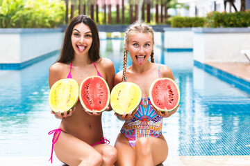 Summer tropical portrait of two pretty young girls having fun near pool