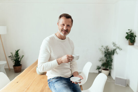Relaxed sporty middle-aged man enjoying a cup of tea or coffee