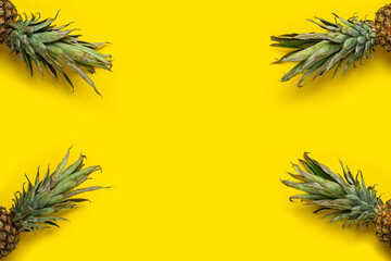 Green foliage of pineapple on a yellow background. Top view, flat lay