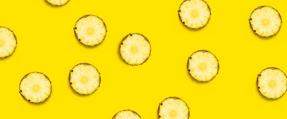 Round pineapple slices on a yellow background. Top view, flat lay. Banner