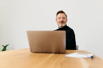 Middle-aged man smiling while thinking of future during work