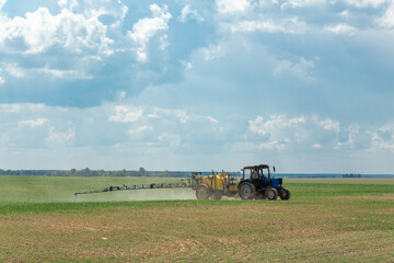 Fototapeta premium Tractor sprays liquid chemical fertilizers