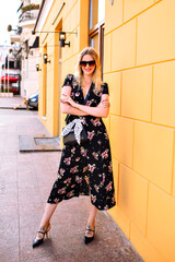 Outdoor fashion portrait of stylish blonde woman wearing sexy vintage midi floral dress