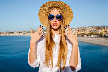 Pretty blonde woman wearing trendy straw hat and blue sunglasses