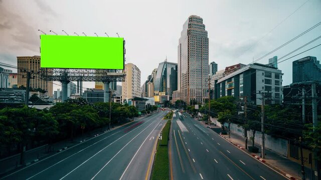 Time-lapse of traffic in Bangkok buildings in the business area and car trails. The signpost billboard banner set on a green screen.