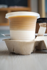 Blurry photo of a cold latte drink in a plastic cup in a takeaway holder.