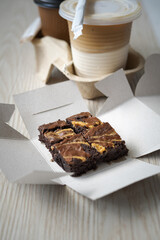 Freshly baked brownies with hot and cold latte in a takeaway cups.