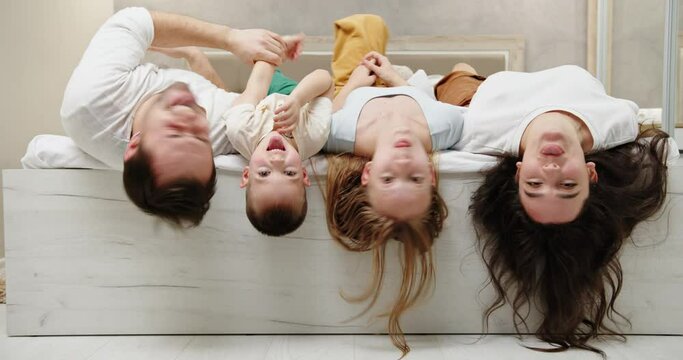 Happy family lying on bed and grimacing