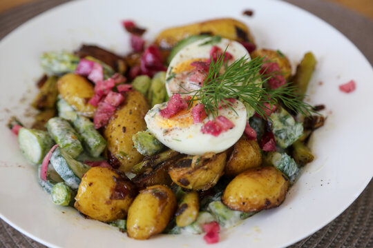 lukewarm salad with fried potatoes, green asparagus, cucumber, diced onion and egg seasoned with dill