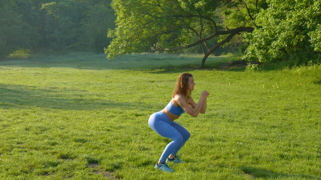 Young beautiful girl doing fitness workout on the grass in the park