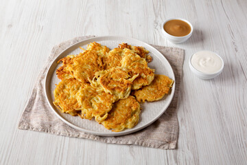 Homemade Potato Pancakes Latkes with Apple Sauce and Sour Cream on a white wooden background, low angle view.