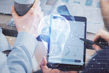 Double exposure of man's hands holding and using a digital device and bulb hologram drawing. Idea concept.