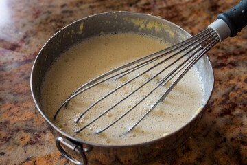 Raw crepes dough. Delicious french recipe. Wick in a metal cooking bowl.
