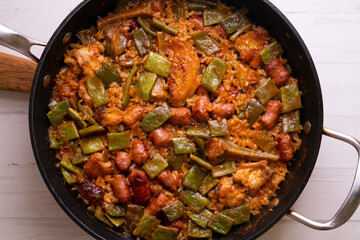 Spanish paella with rabbit, sausages, vegetables and artichokes. Traditional recipe from the Mediterranean area.