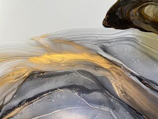 Abstract grey art with gold — black and white background with beautiful smudges and stains made with alcohol ink and golden paint. Grey fluid texture resembles marble, smoke, watercolor or aquarelle.