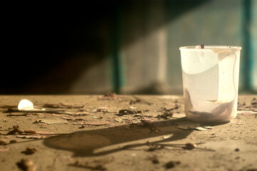 A still life image with an old plastic mug on a devastated table. Plastic mug with a hard shadow in...