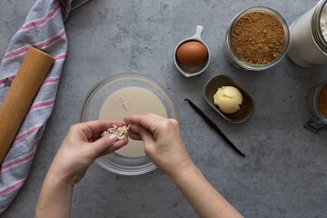 Woman hands pouring yeast over a crystal bowl next to some cinnamon roll ingredients.