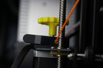 Extruder motor with orange color pla filament for creative manufacturing. Modern 3D Printing machine
