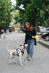 View of young Caucasian female playing and training her dalmatian dog, plus size female spending...