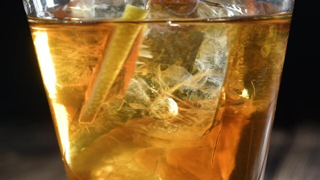 Iced tea in the glass with ice cubes and sliced lemons. Healthy refreshing lemonade for detoxification, sweet tasty soft drink or cold aromatic beverage for summer time in slow motion