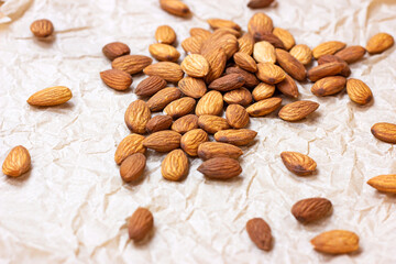 Raw almond nuts heap on light paper background.
