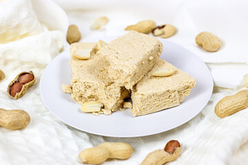 Traditional sweet turkish delight halva pieces with peanut nuts on light background.