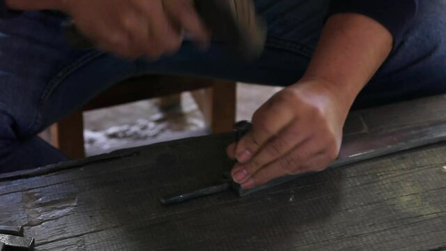 Decorating the Nam Phi sword by nailing the pattern onto the knife