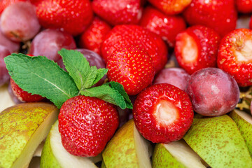 Close up of fresh fruit and berries. Strawberries, slicing pear and grapes. Summer fruit background closeup. Selective focus