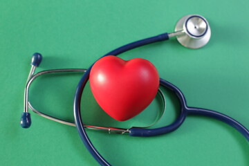 Medical stethoscope and heart on green background