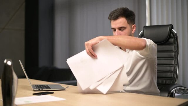The young executive examines the documents then throws them away, freaking out. The manager in the office is upset with the results of the work and is angry