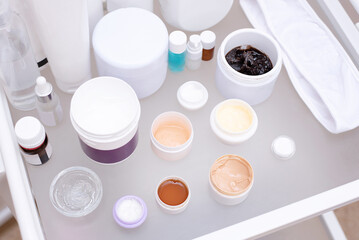 Many jars with various creams on a glass table in a beauty salon, facial skin care concep.