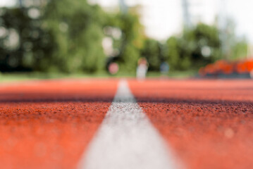 Outdoor stadium jogging track. Texture of red rubberized surface with a white line in the middle....