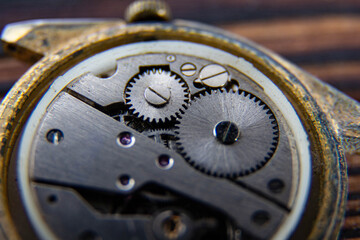 The movement of an old mechanical watch on a wooden background.