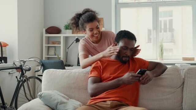Young African woman covering eyes to her boyfriend while spending time at home