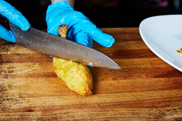 the chef cuts a Kiev cutlet on a wooden board