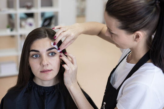 The master plucks wax strips or a paper shugaring bandage from the eyebrows. Waxing of the eyebrows.