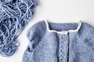 blue knitted product on knitting needles on a white background