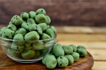 wasabi coated nuts with a wooden background