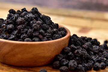 Organic Aronia berries in a wooden bowl